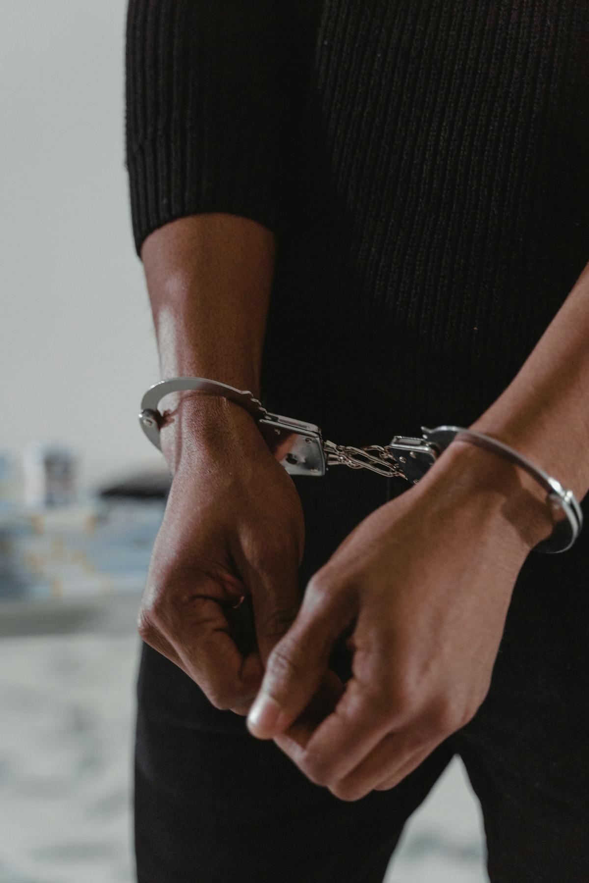 Person with hands in handcuffs during arrest - temporary restraint versus long-term monitoring