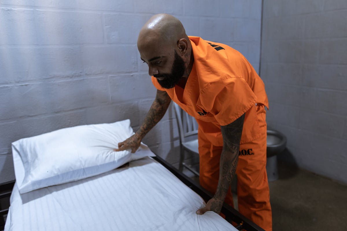 Correctional officer conducting security check in facility housing unit - RTLS technology automates presence verification and movement tracking that traditionally requires manual officer rounds